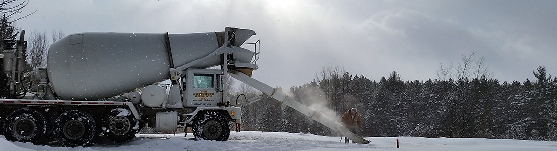 Concrete mixer truck delivering Redimix concrete on a snowy construction site in Northern Michigan.