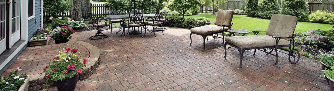 Outdoor patio with brick pavers and comfortable seating, surrounded by a well-maintained garden using Sealants and Chemicals.