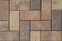 Interlocking Patio Pavers in Earth Tones Close-up of interlocking patio pavers in a variety of earth tones, arranged in a herringbone pattern.