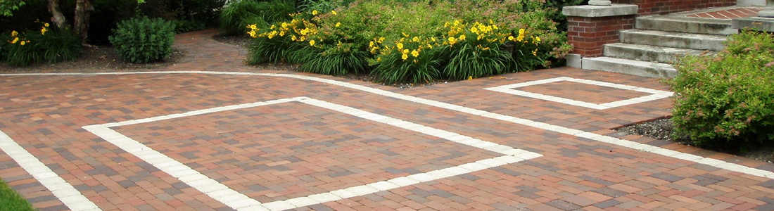 Brick walkway and patio design with decorative border, surrounded by vibrant landscaping and garden steps.